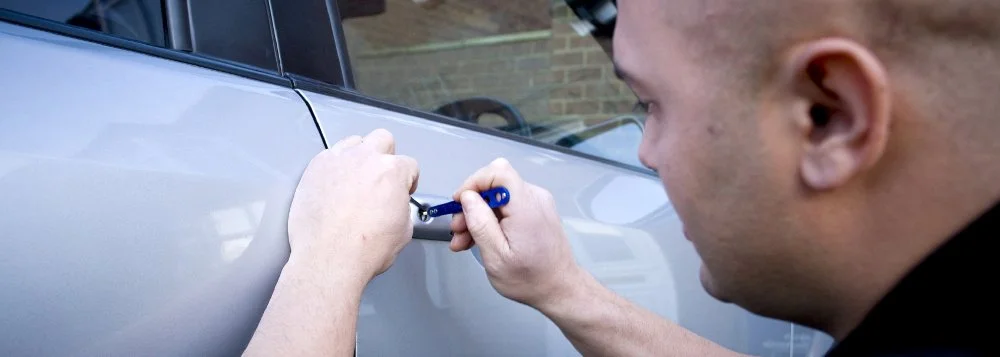 A man using a screwdriver to work on a car door.