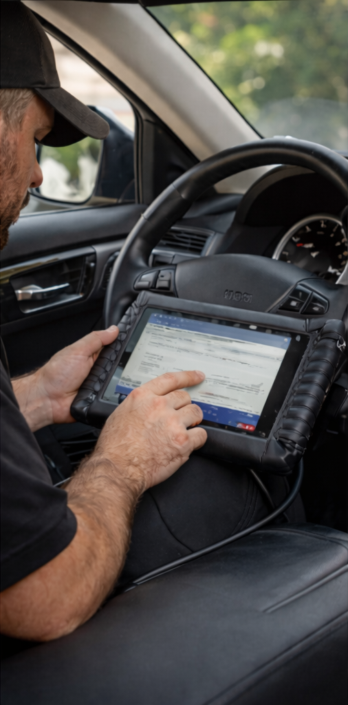 A man operating a diagnostic scanner inside a vehicle.