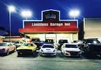 A car dealership named Limitless Garage, LLC at night with multiple cars parked in front and brightly lit signage.