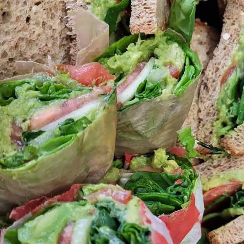 Close-up of fresh vegetable wraps filled with lettuce, tomato, and other vegetables, served with bread slices.