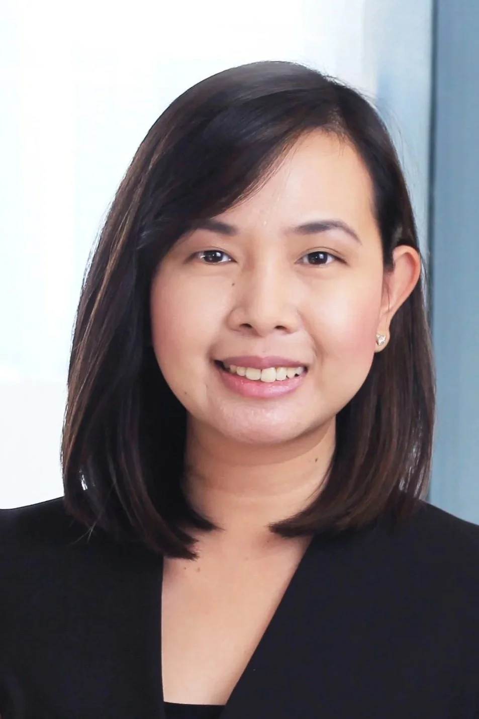 A young woman with shoulder-length dark hair and a slight smile, wearing a black top and small earrings.