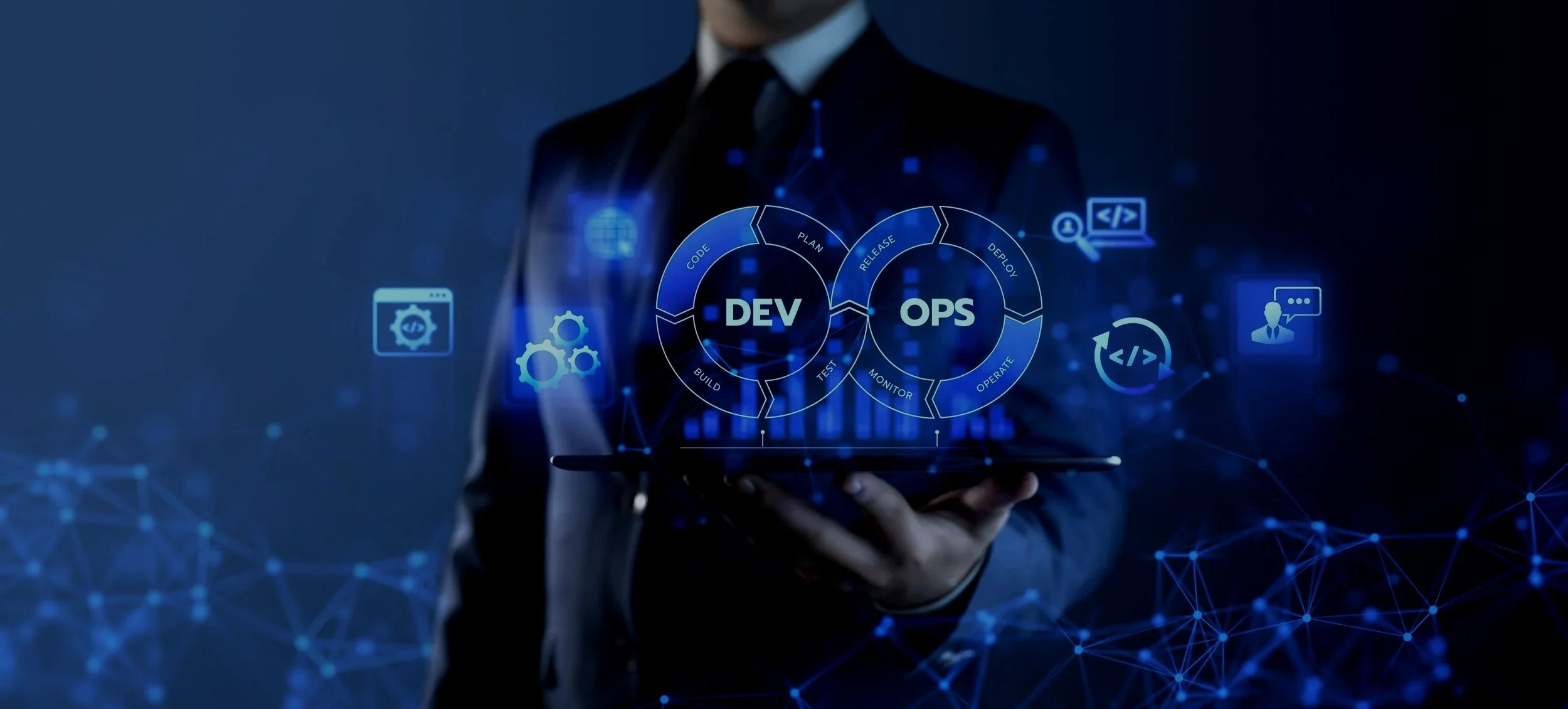 Businessman in suit holding a tablet with a digital interface showing DevOps cycle, gears, coding, and communication icons in a dark blue background.