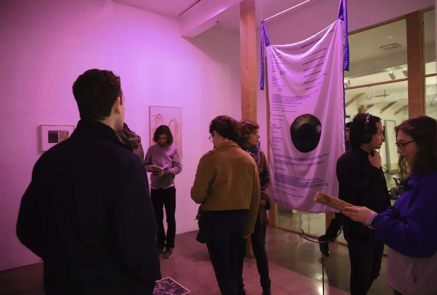 People observing and engaging with artwork in an art gallery, with pink lighting illuminating the scene at Navel in Los Angeles.
