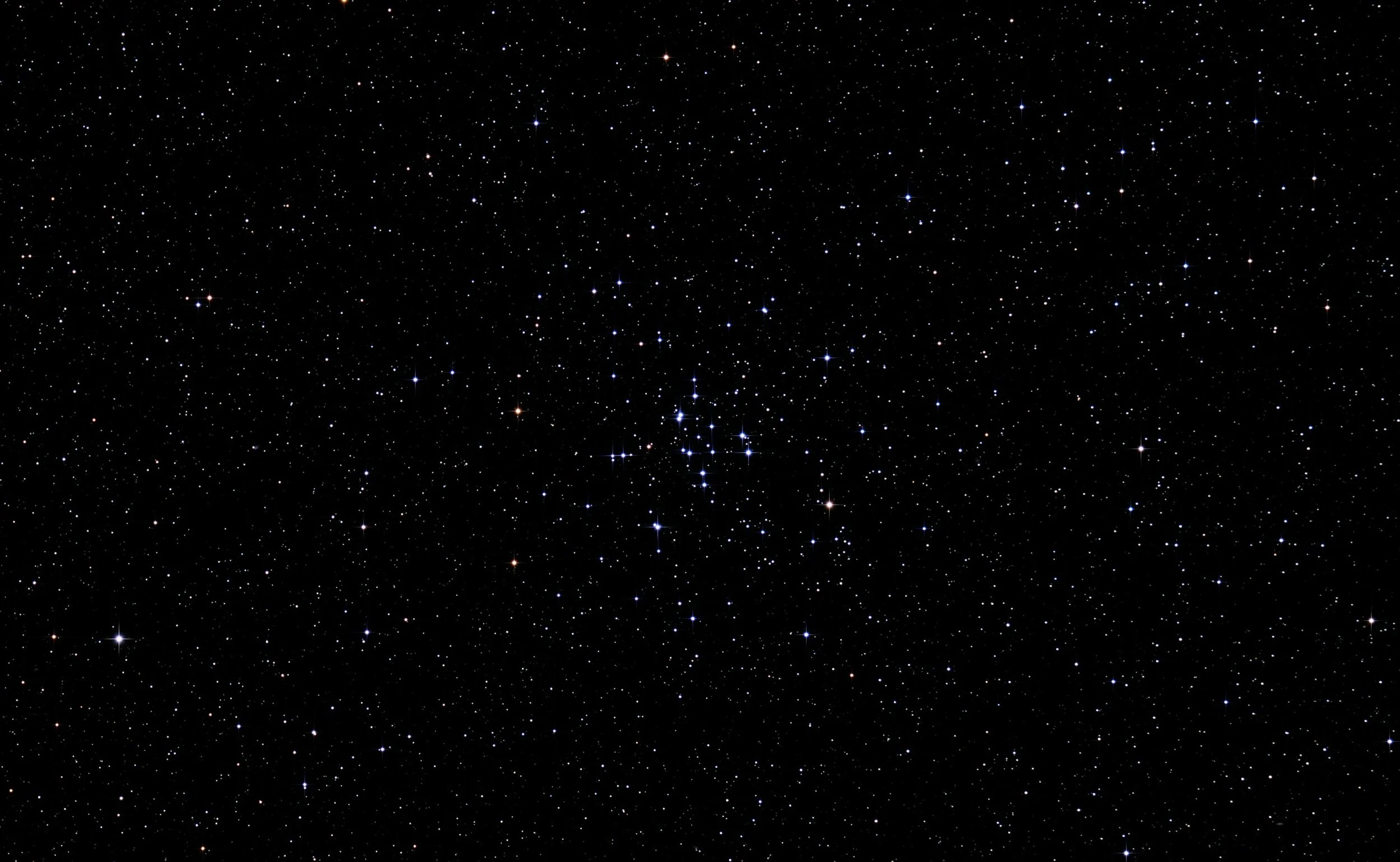 A clear, infinite night sky filled with numerous stars of varying brightness and color, with some stars forming small clusters.