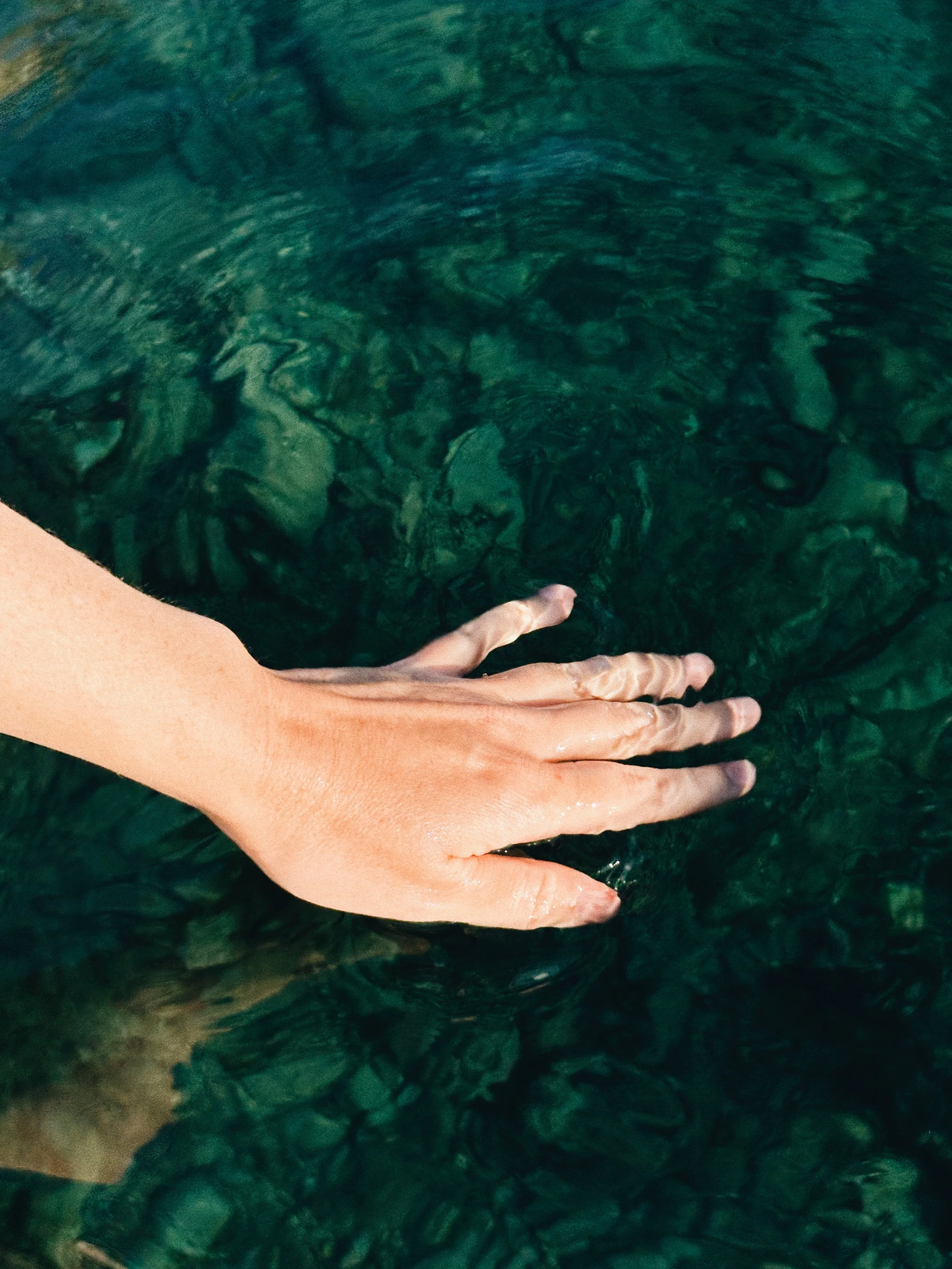 Mano tocando el agua en experiencia nocturna de bioluminiscencia en el Cap de Creus