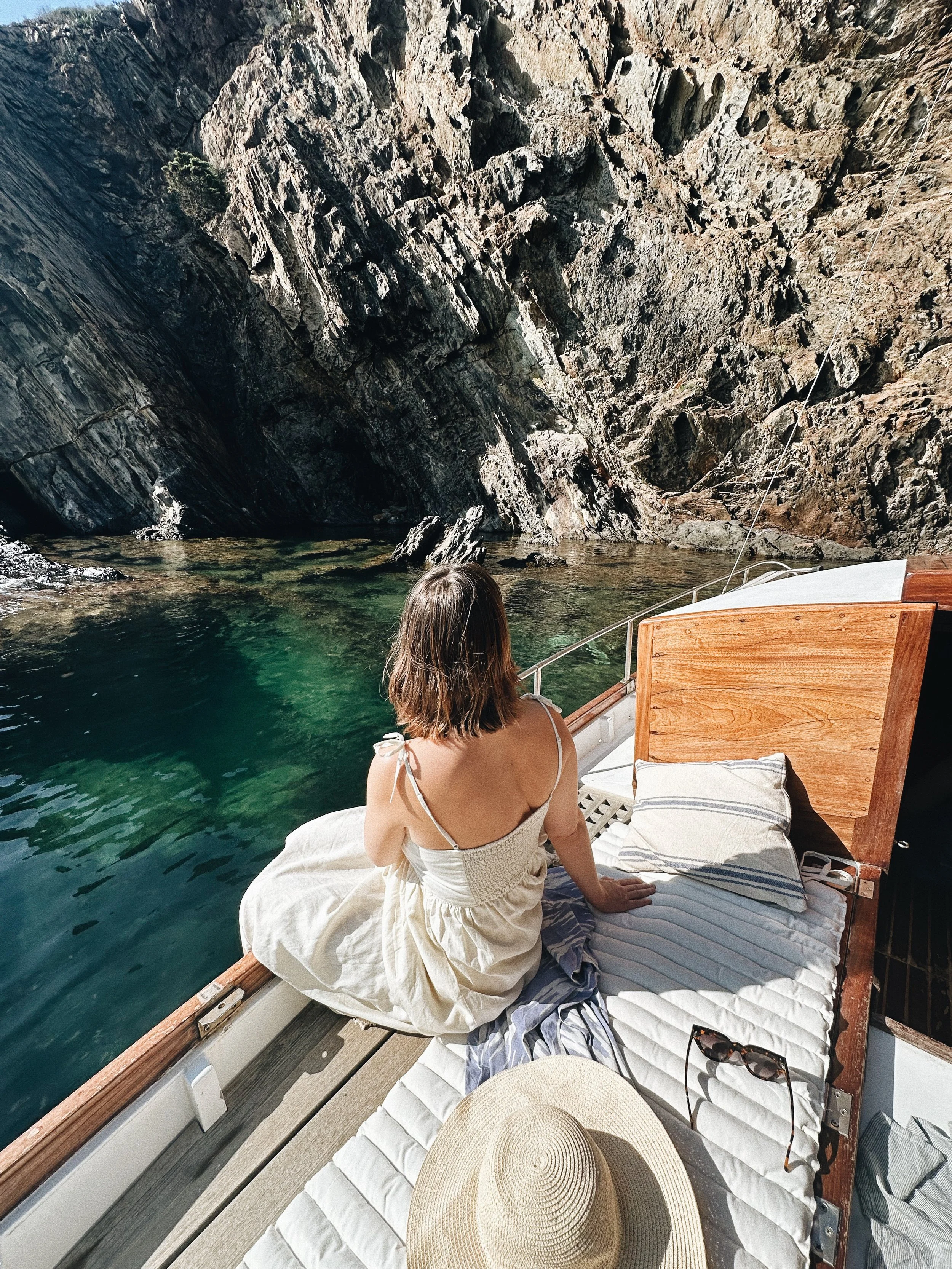 Mujer disfrutando de cala cristalina desde un llaut tradicional en Cadaqués