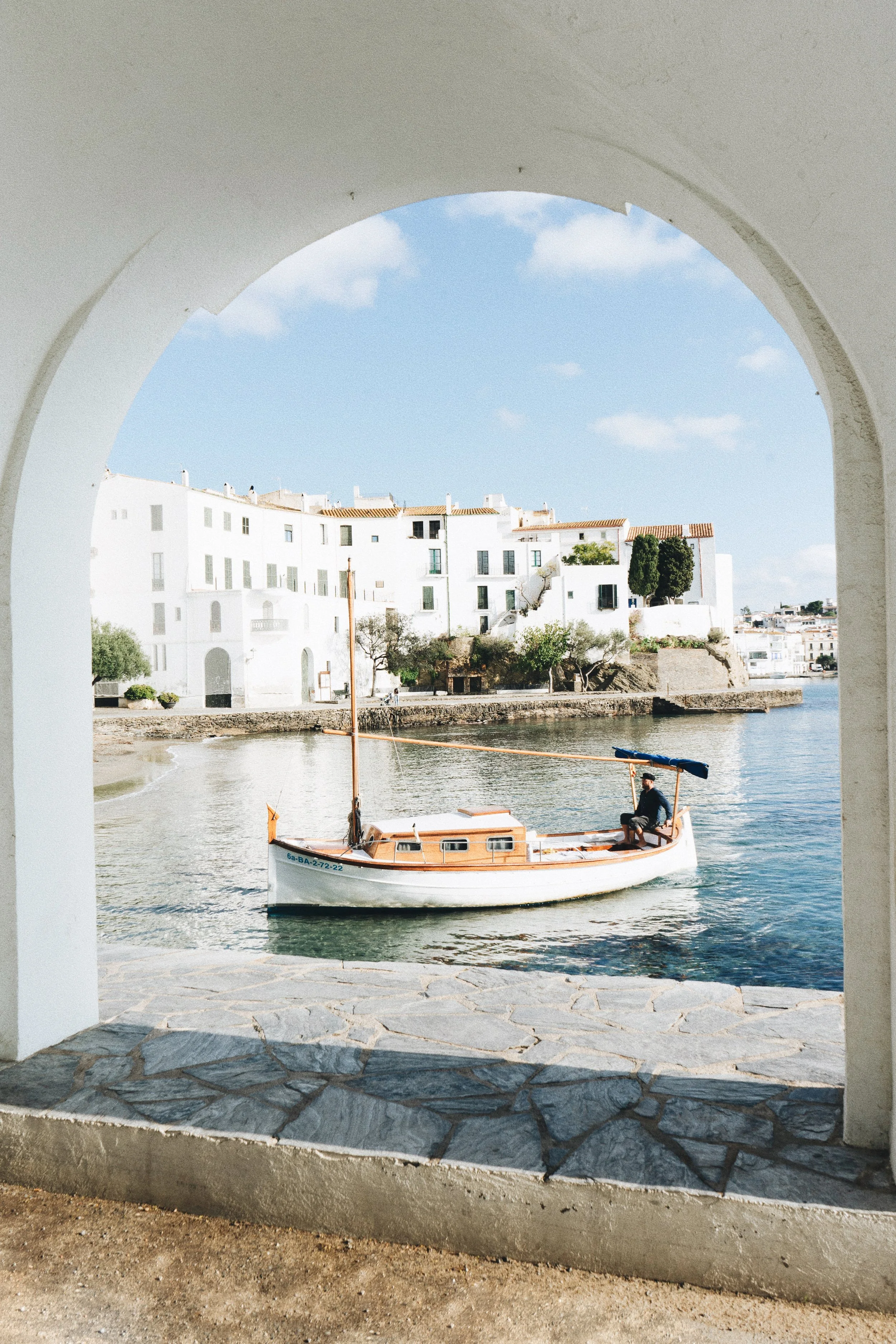 Barco tradicional navegando frente al pueblo de Cadaqués