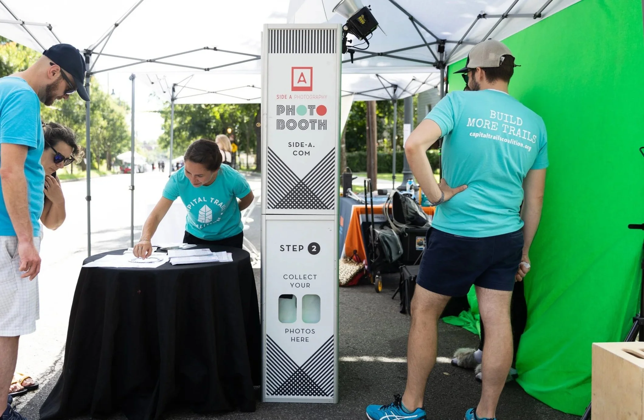 A group of people check out the photo booth and green screen during an Open Streets event.