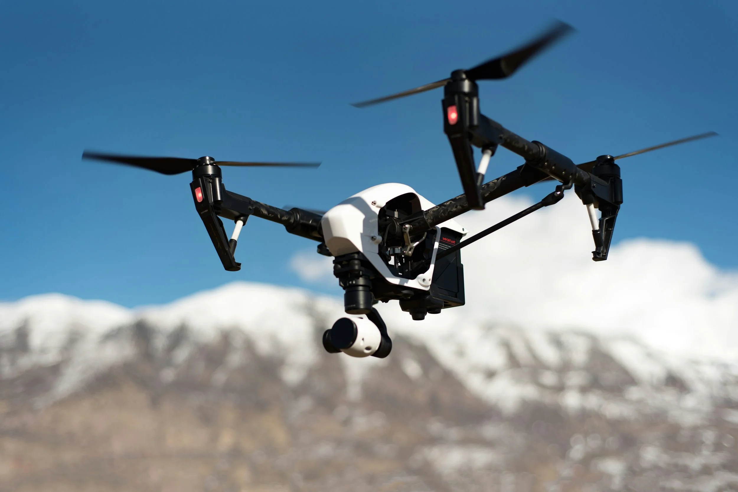 A drone flying in the sky with snow-capped mountains in the background.