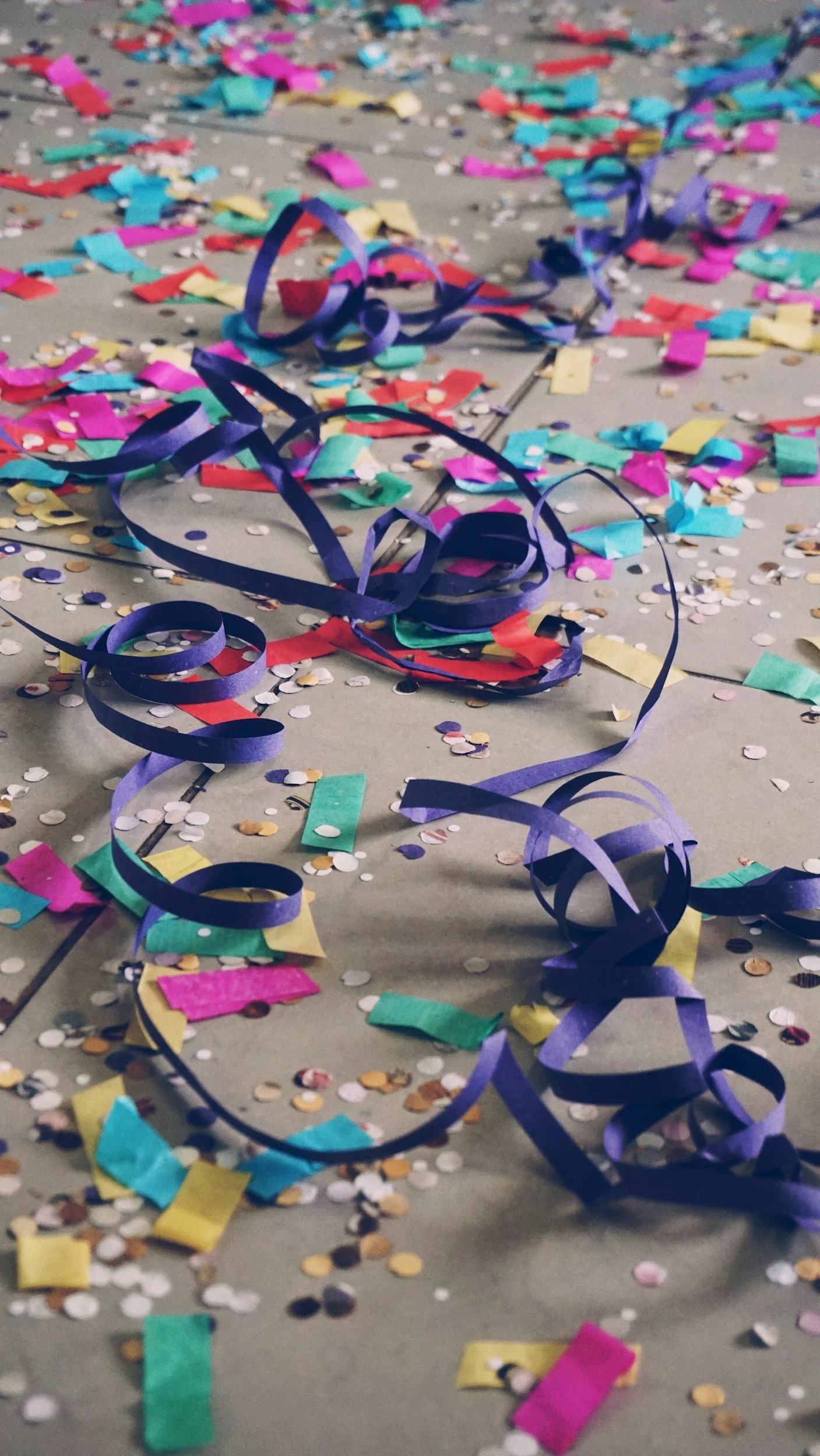 Colorful confetti, streamers, and paper scraps scattered on the floor, likely from a celebration or party.