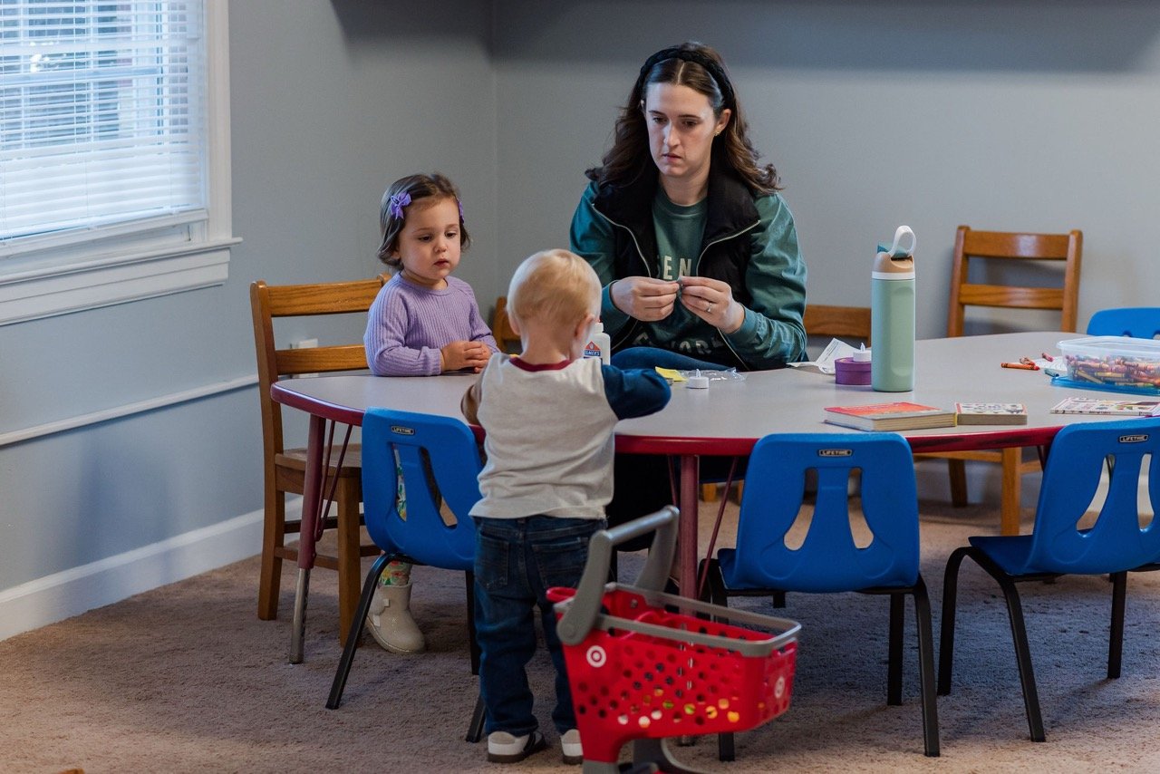 Children at a table participating in an arts and crafts activity, working with colorful tissue paper and brushes in a classroom setting.