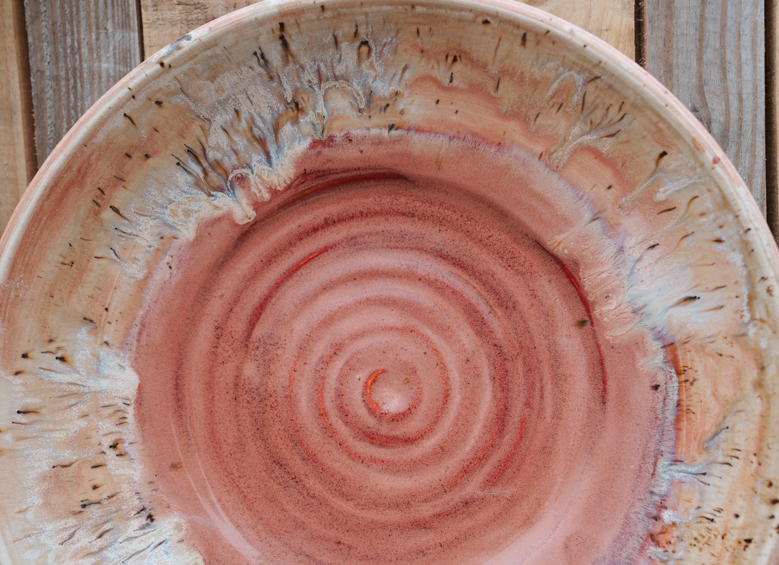 Close-up of a pink and beige ceramic bowl with a spiral pattern, placed on a wooden surface.