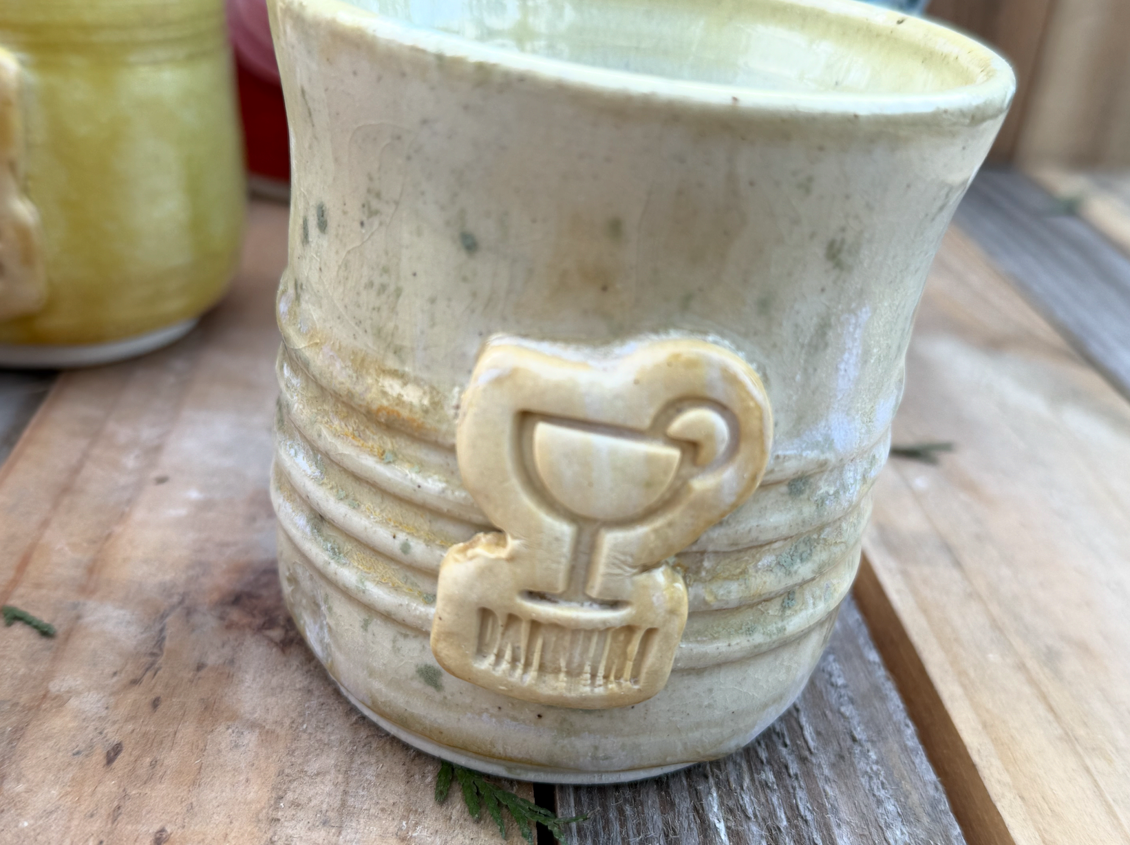 Close-up of a ceramic mug with a vintage trophy design on its side, placed on a wooden surface.