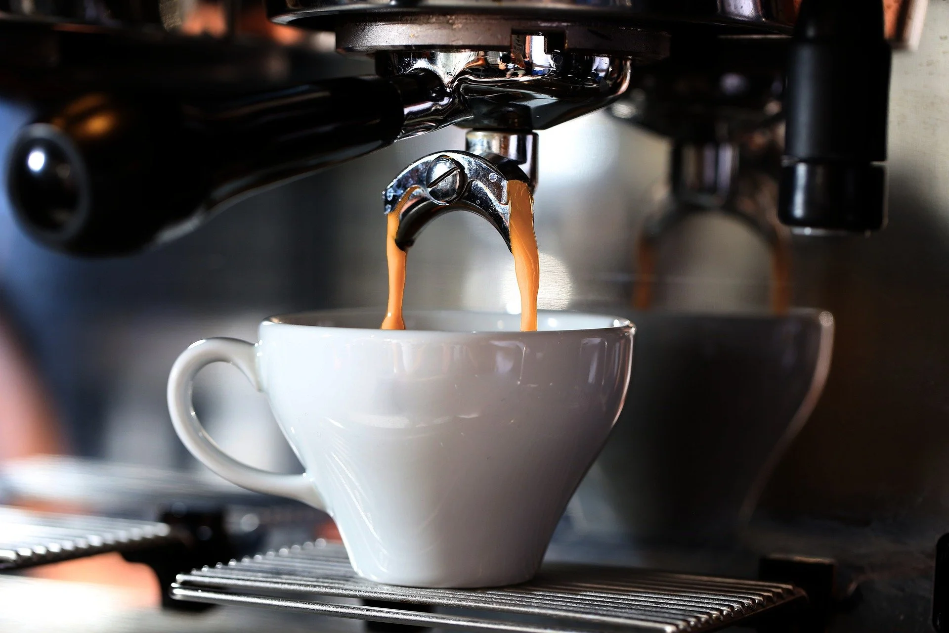 Coffee being brewed from an espresso machine into a white cup.