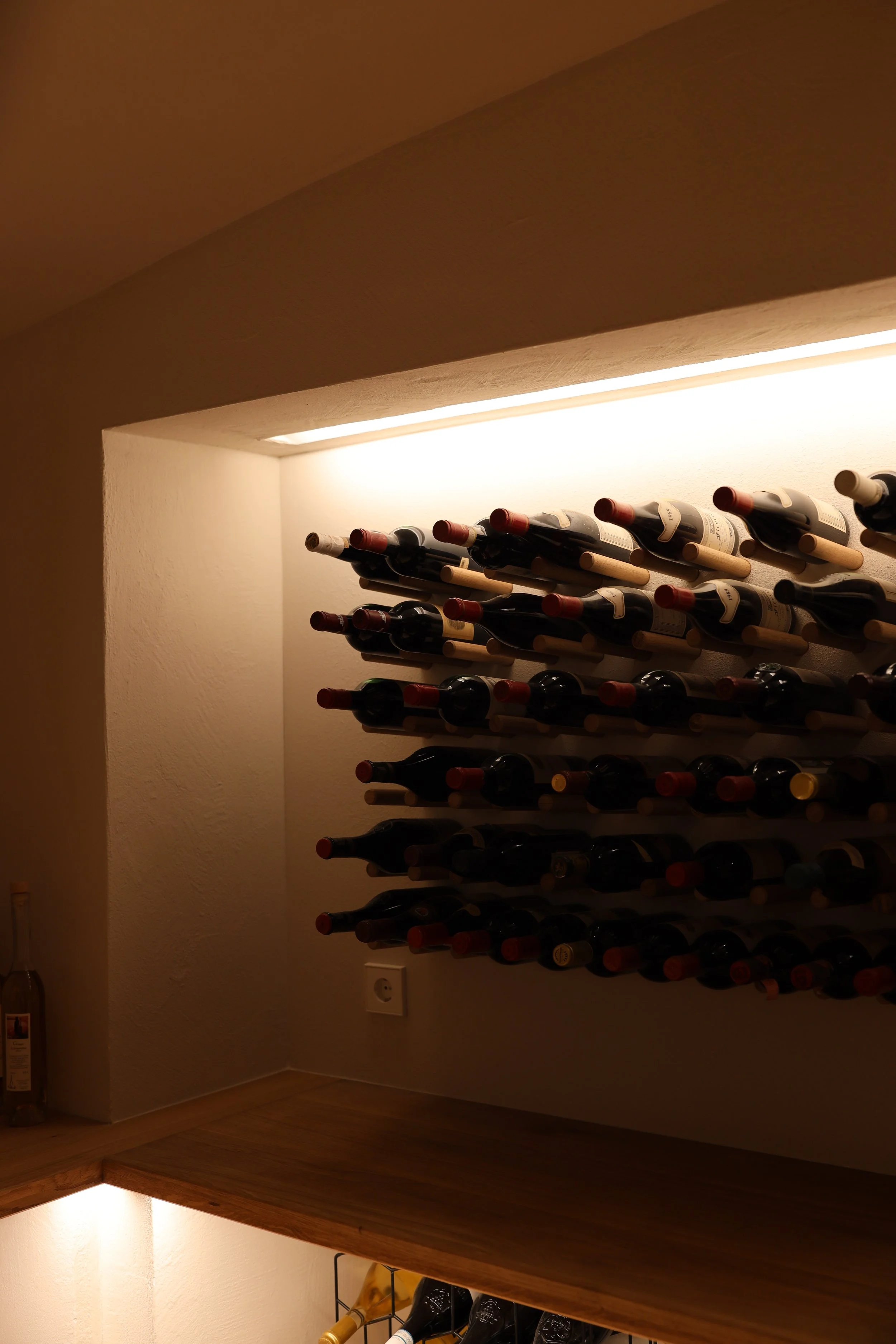 Weinregal mit mehreren Flaschen Wein in einem Kellerraum.
