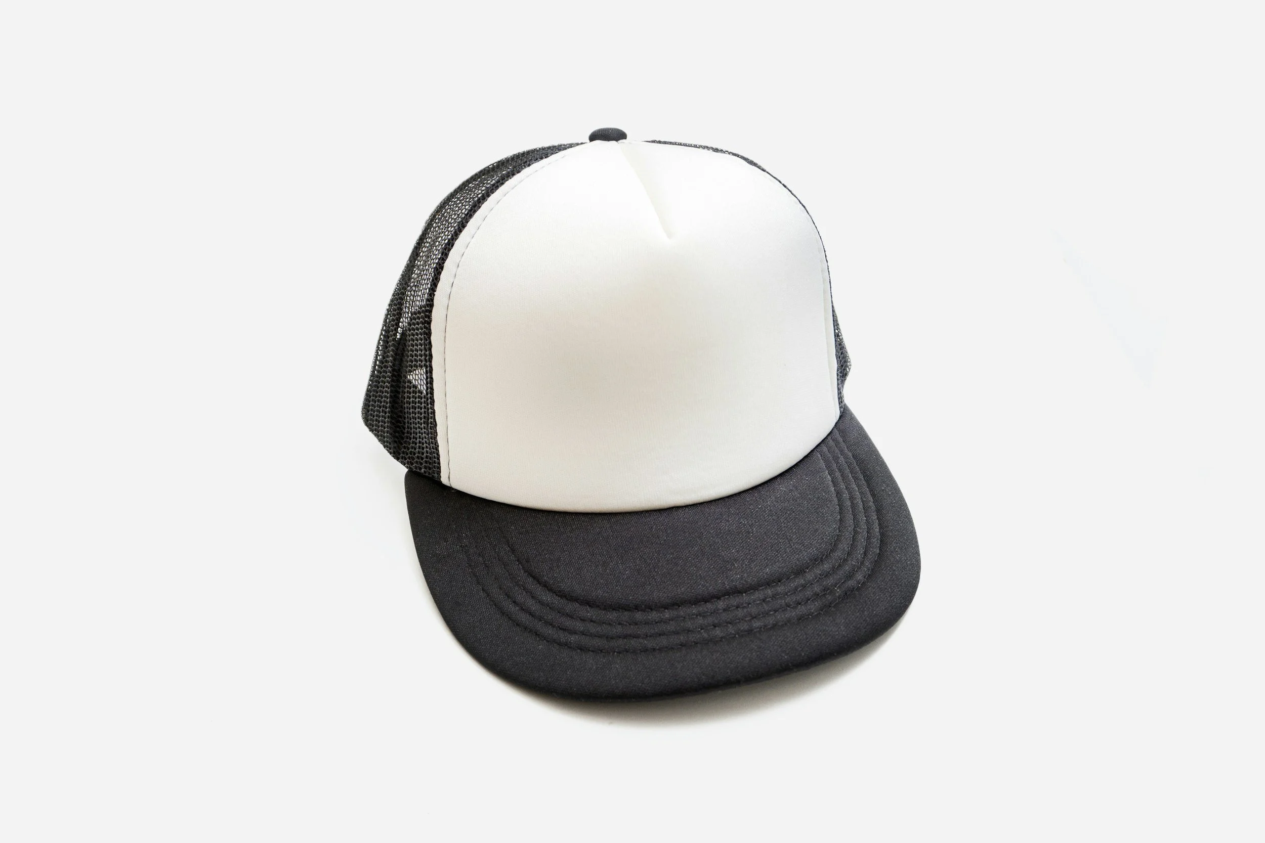 A black and white trucker cap with a black brim and mesh sides