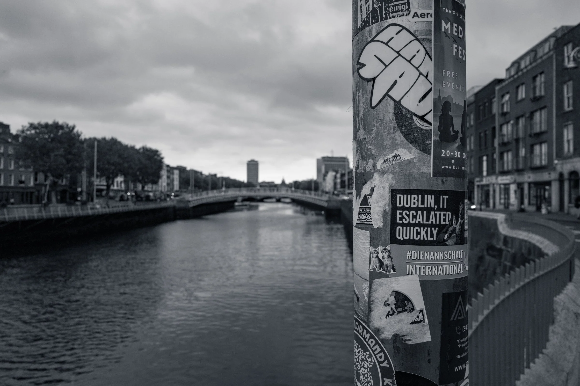 The gable ends of Dublin buildings under a heavy grey sky, in black and white, with large painted artwork across the brickwork.