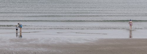 Two distant figures standing on the wet sand at low tide across the wide expanse of Portmarnock beach, Dublin.