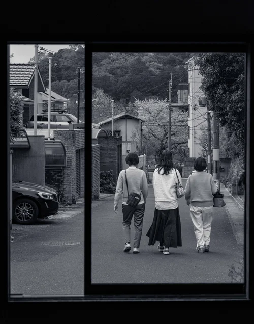 Two figures in kimono walking away down a street, framed through a dark doorway, Kyoto, in black and white.