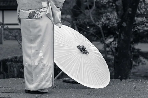A close view of a person in kimono holding a large paper parasol, Kyoto, in black and white.