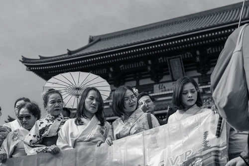 Women in kimono with a paper parasol before the temple hall at Senso-ji, Tokyo, in black and white.