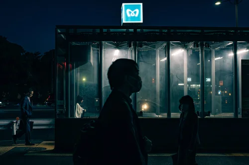 A figure silhouetted against the glow of a metro station entrance at night, Tokyo.