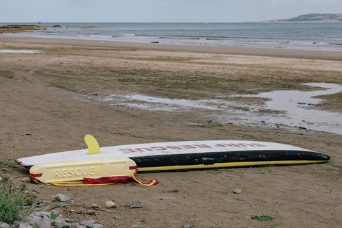 An upturned rowing boat resting on the sand at Portmarnock beach, Dublin, the tide far out and a headland in the distance.