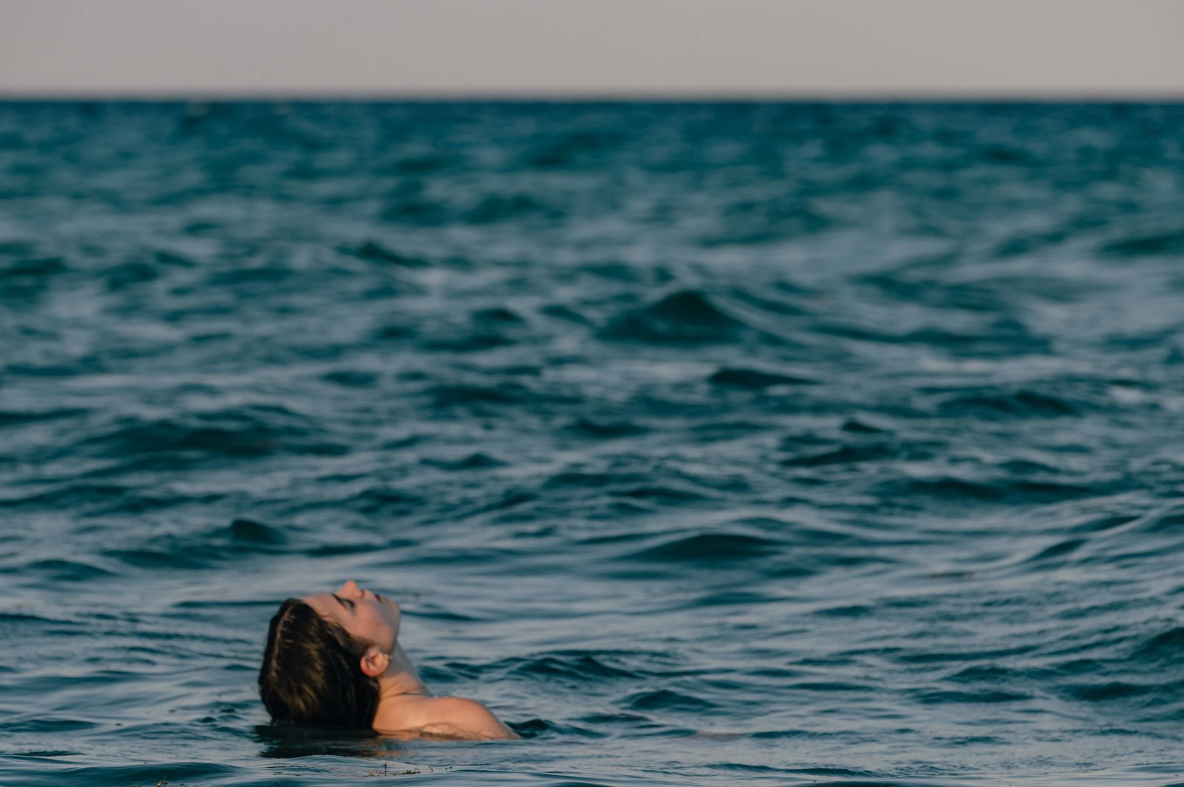 A woman floating in open water off Miami Beach with her head tipped back and her eyes closed, the sea filling the rest of the picture.