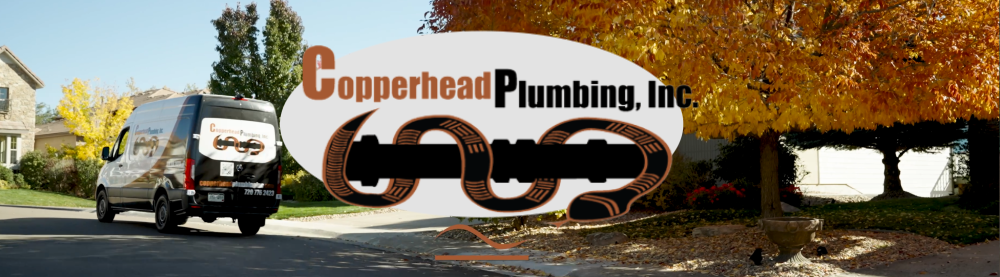 A van parked on a suburban street with a large sign displaying the logo and name of Copperhead Plumbing, Inc., featuring a chain and pipe graphic, with autumn trees and houses in the background.
