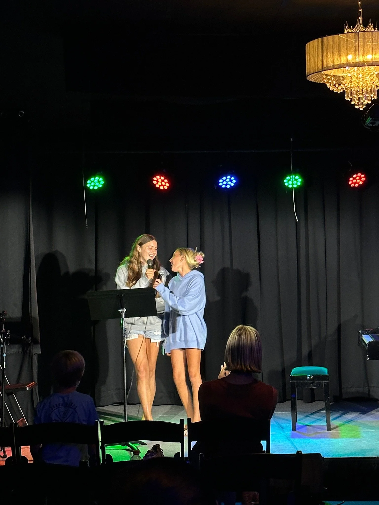 Microphone standing on a stage with bright lights in the background.