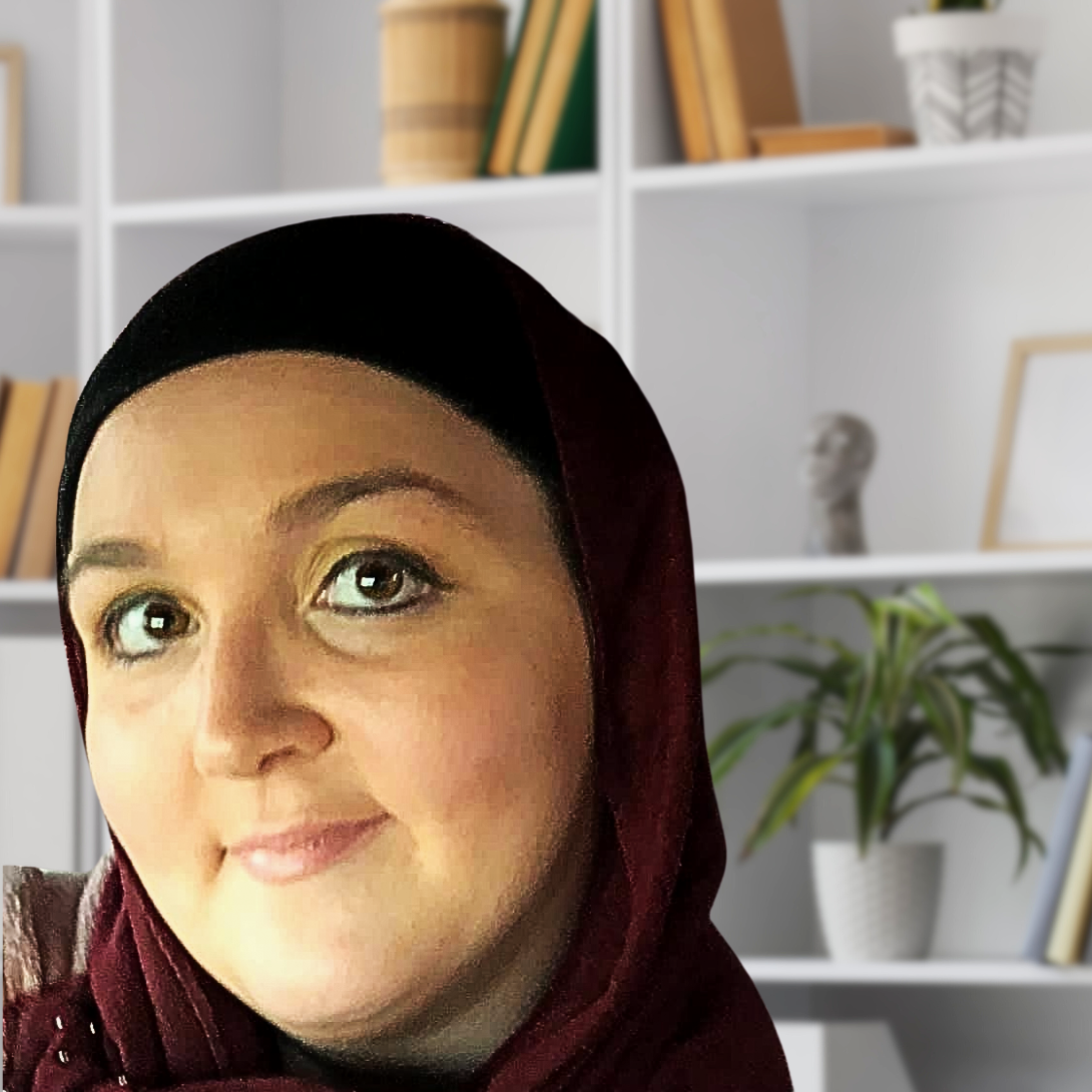 A Muslim woman, Jennifer Aboufadle, wearing a black and burgundy headscarf smiling, with a bookshelf and a potted plant in the background.