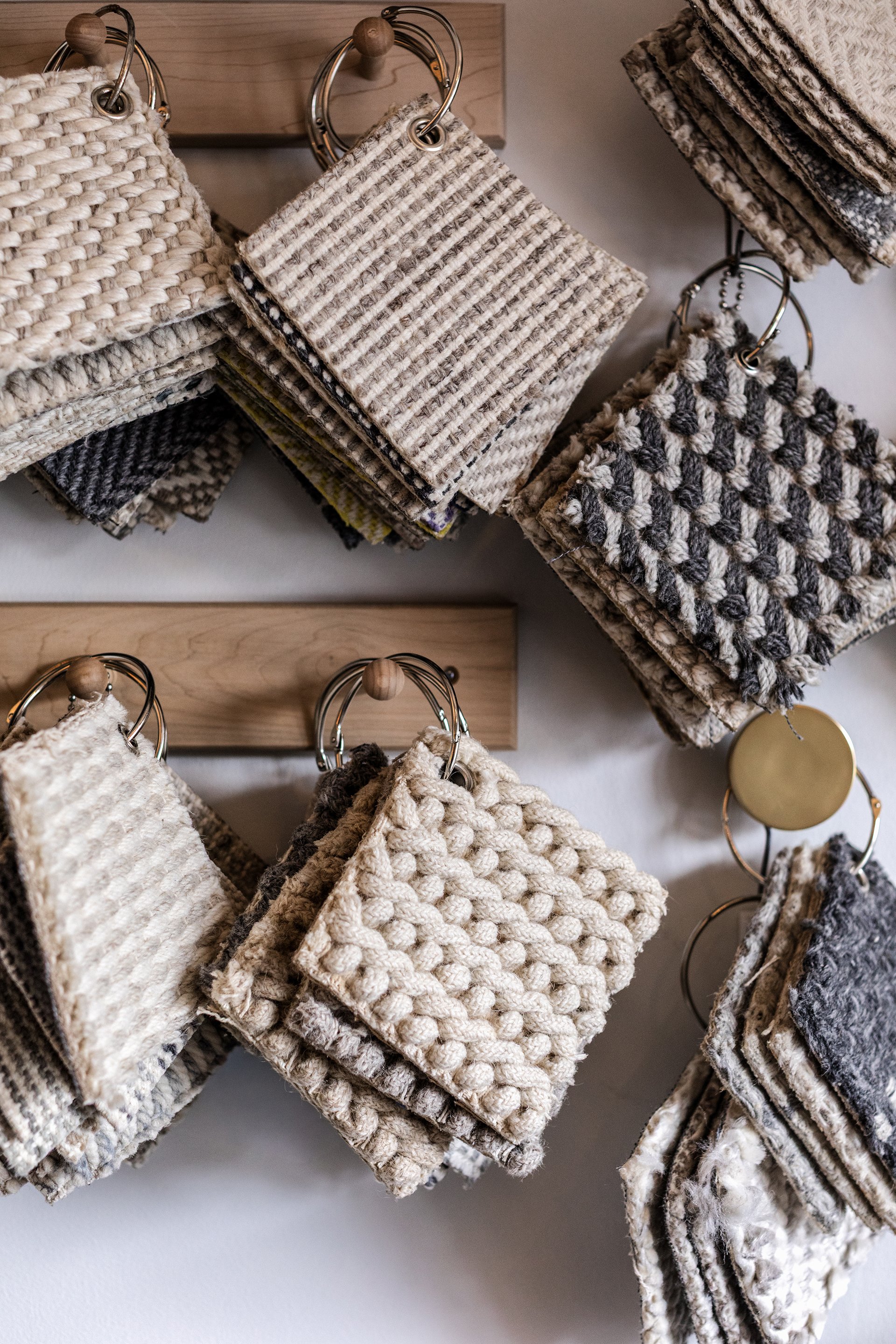 Sample swatches of fabric or carpet samples hanging on metal rings with wood and metal accents.