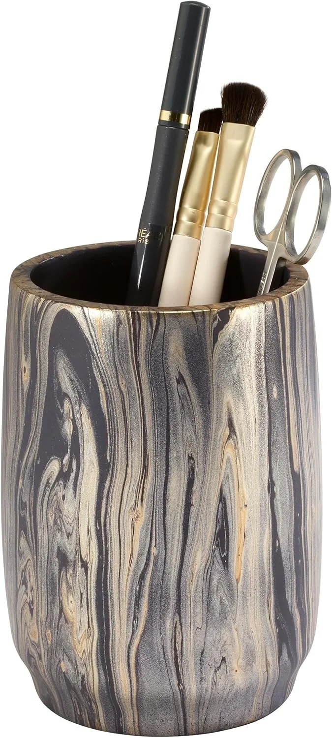 A marble-patterned container holding makeup brushes and scissors.