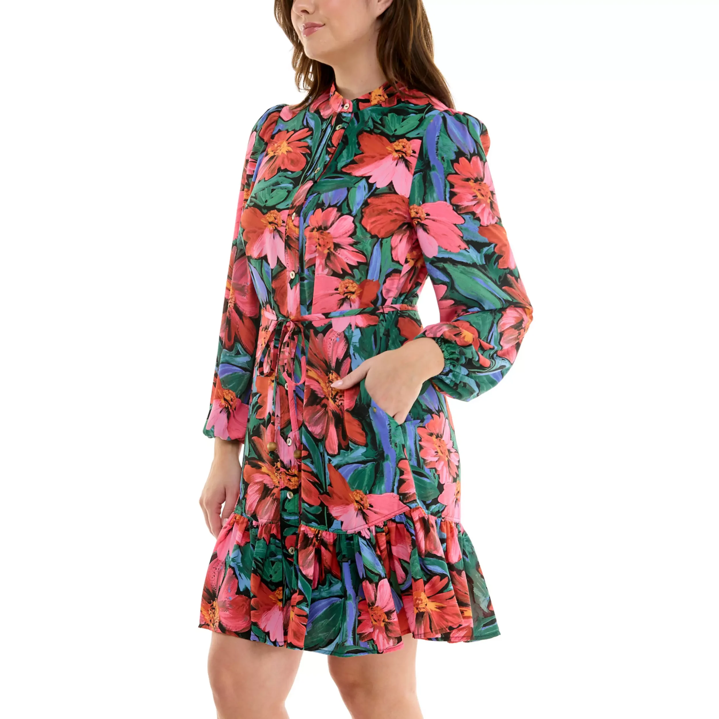 Woman wearing a long-sleeve floral dress with a drawstring waist, standing with one hand in her pocket.