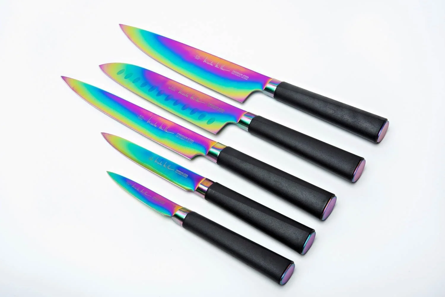 Set of five rainbow-colored kitchen knives with black handles, arranged diagonally on a white surface.