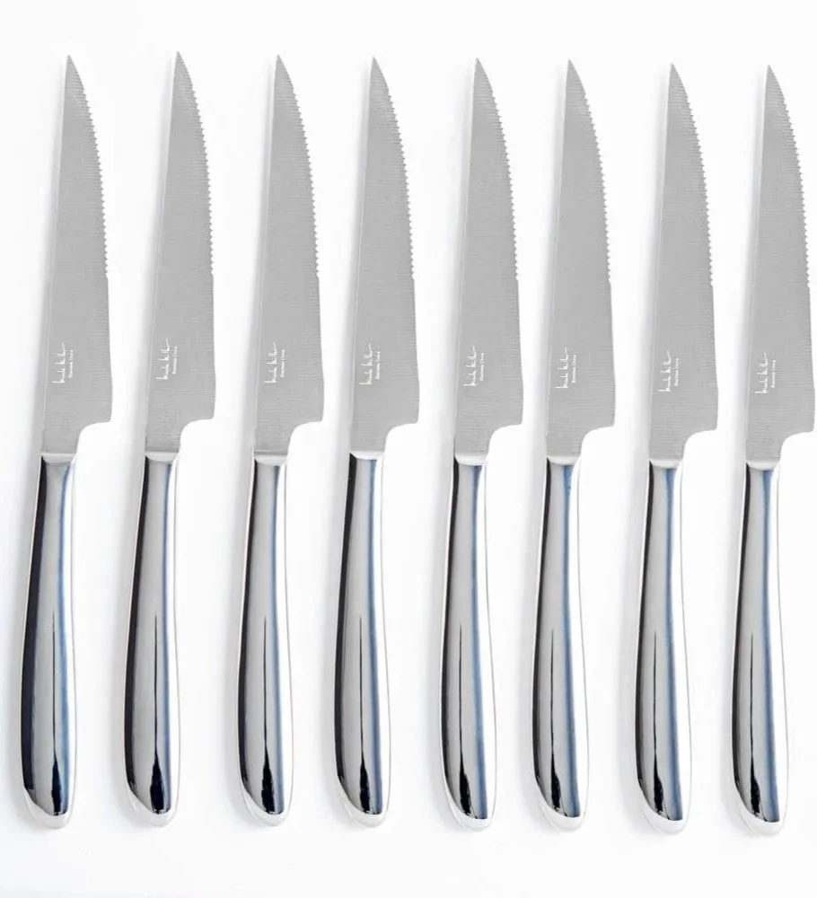 A row of seven stainless steel serrated knives with black handles on a white background.
