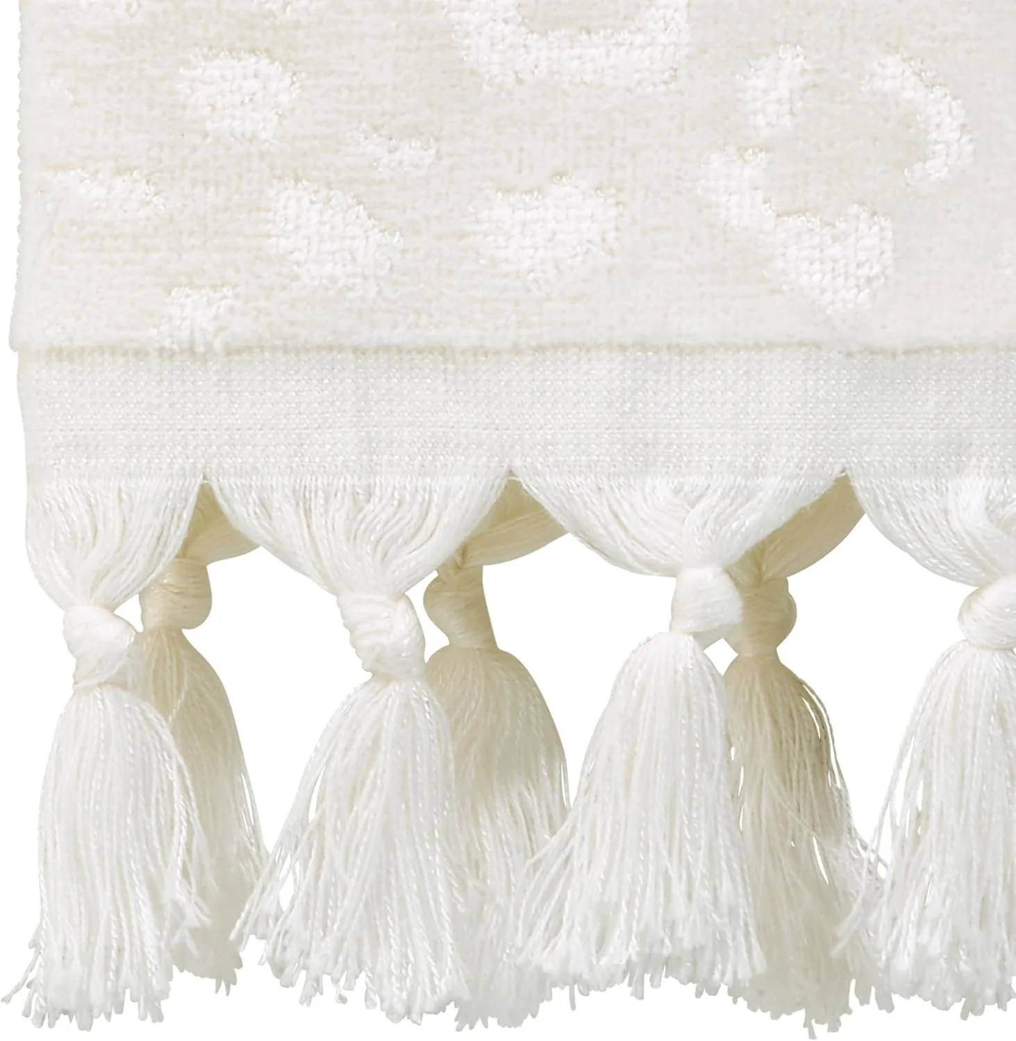 Close-up of a white fabric with decorative tassels hanging at the bottom.