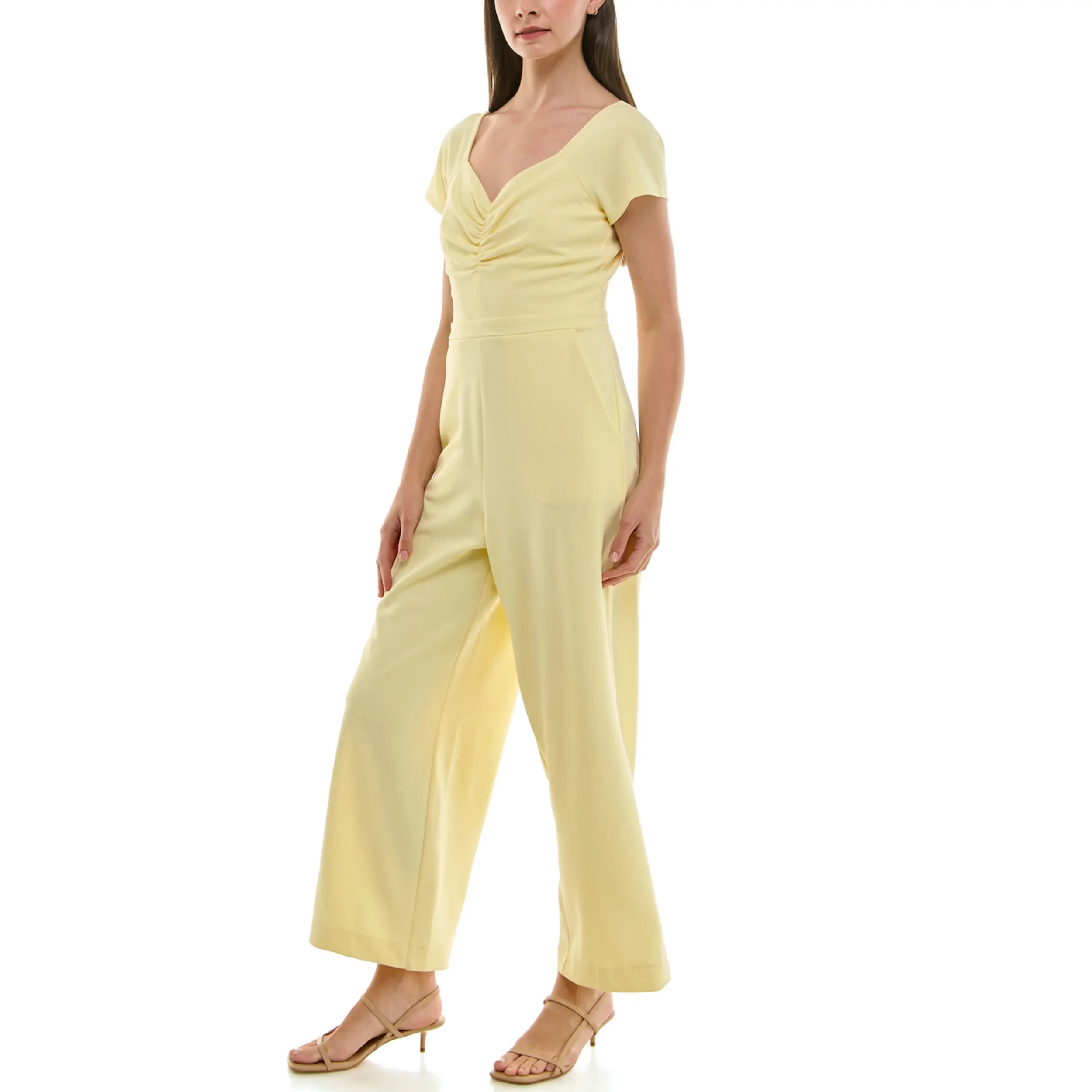 A woman in a light yellow jumpsuit with cap sleeves, a gathered V-neckline, and wide-leg pants, standing against a white background.