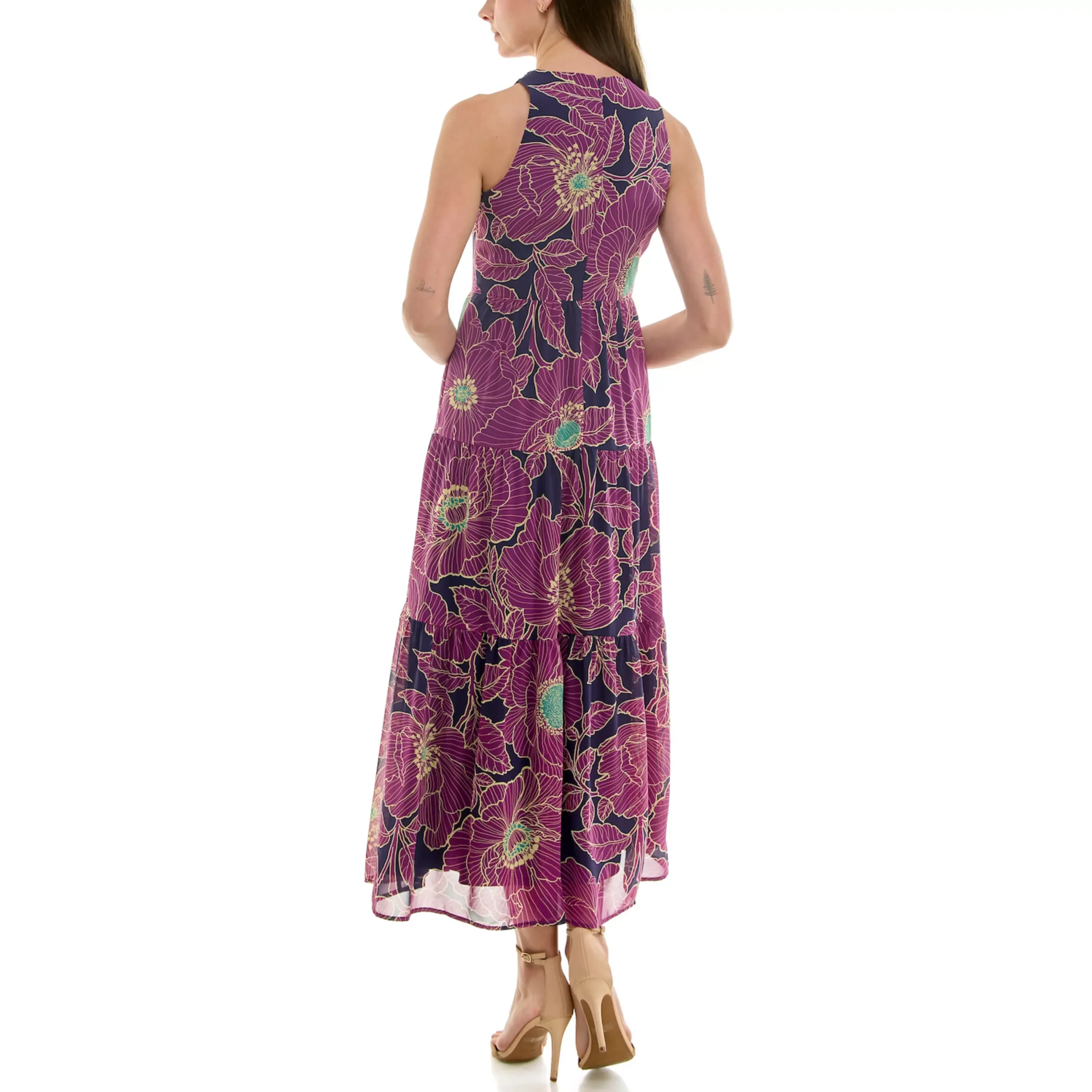 Back view of a woman wearing a sleeveless, floral, mixed-media maxi dress with purple, pink, and green flowers, and beige high heels.