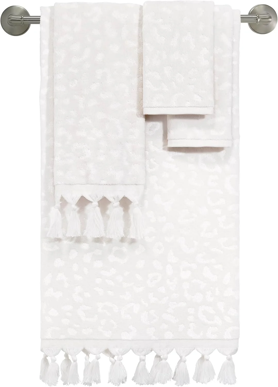 White towel set with tassels hangs on a metal towel rack
