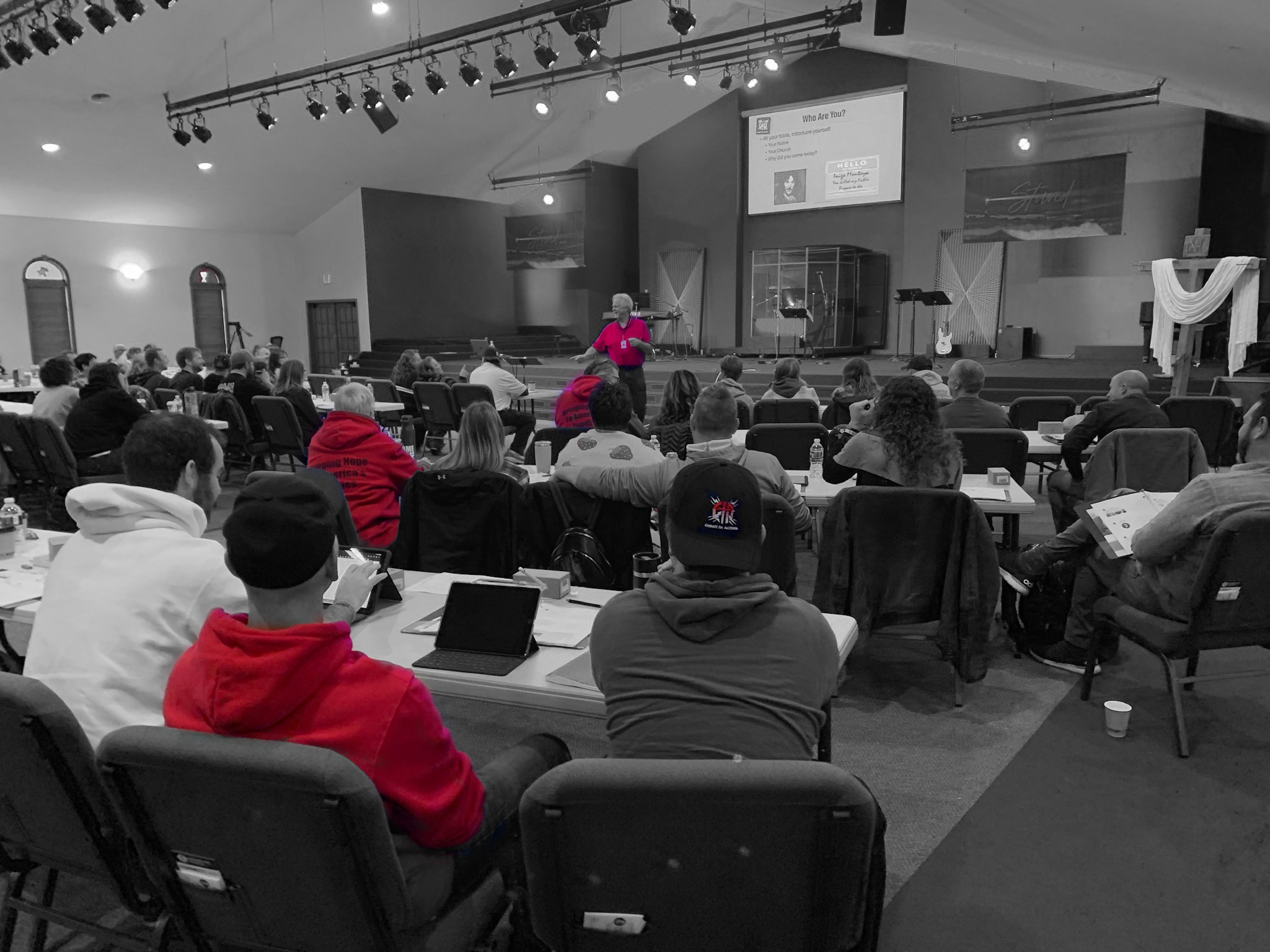 Christ In Action instructor in a red shirt talking with participants during a Disaster Preparedness Seminar classroom session.