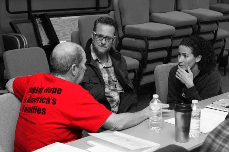 Christ In Action instructor in a red shirt talking with participants during a Disaster Preparedness Seminar classroom session.