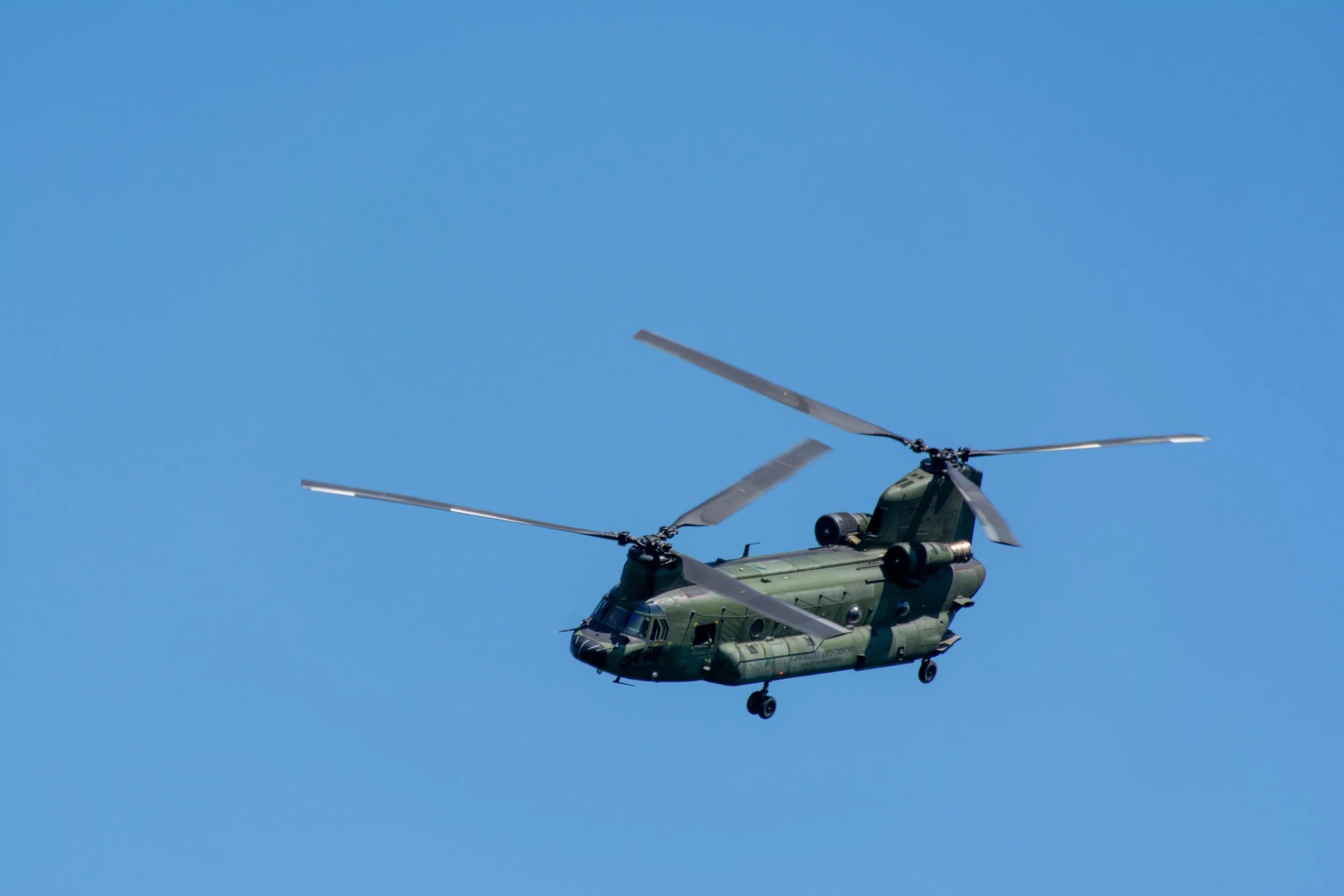 A military helicopter flying in a clear blue sky.
