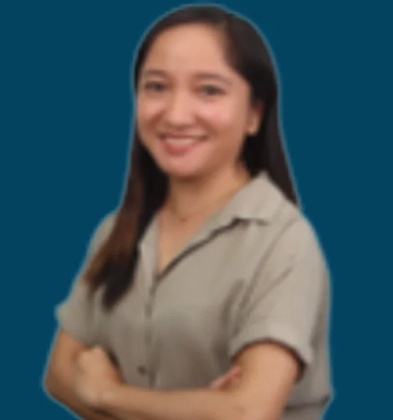 A woman with long dark hair smiling with crossed arms, wearing a beige shirt, against a solid blue background.
