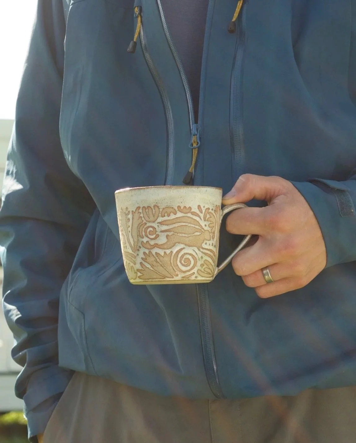 A photo of a person holding a mug with folk-art inspired design
