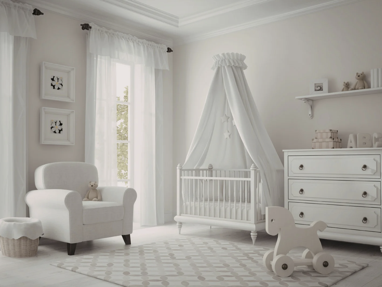 A nursery room decorated in white with a crib, armchair, rocking horse, and dresser, featuring sheer curtains, wall art, and soft toys.
