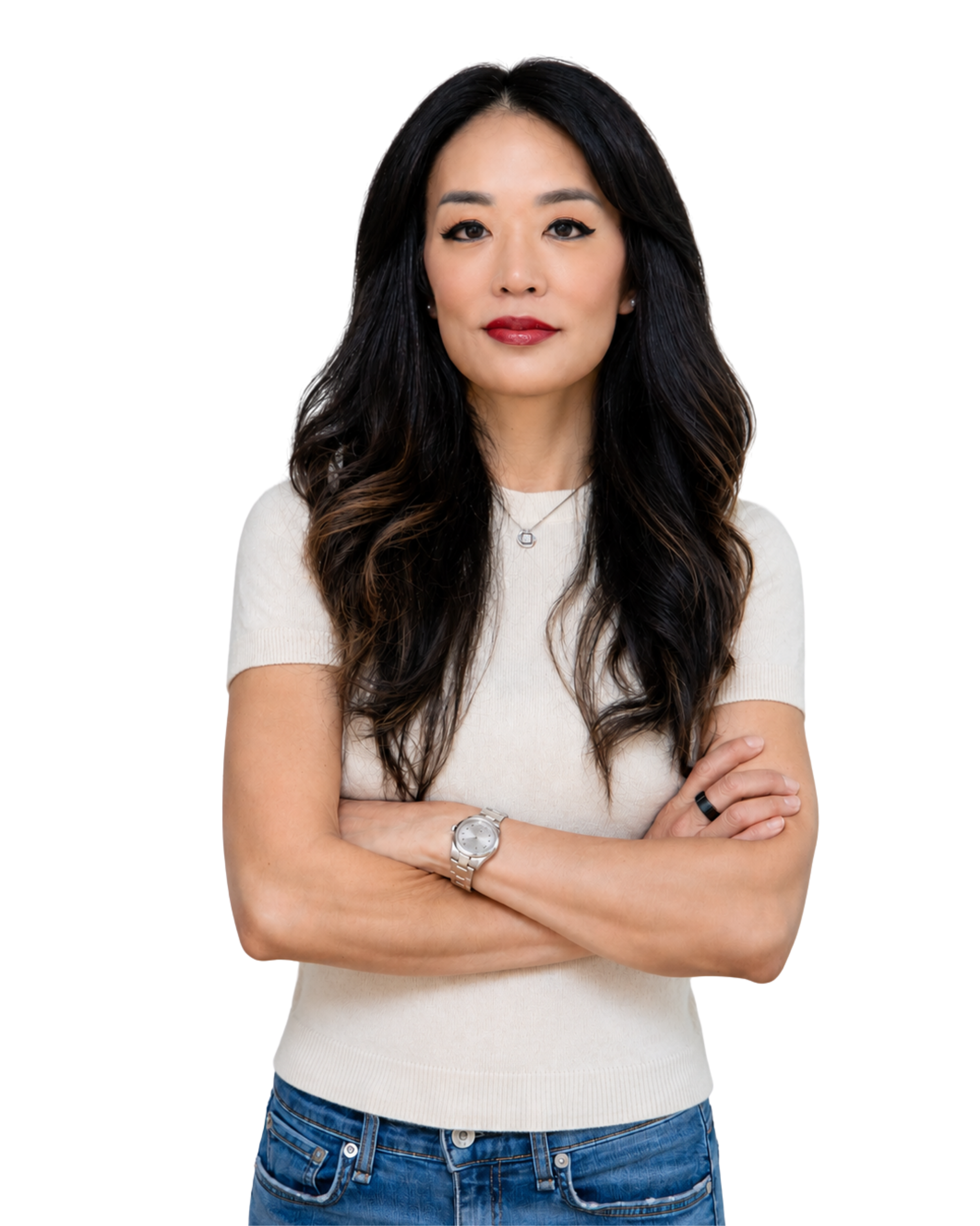 A woman with long dark hair, wearing a white short-sleeved sweater, a silver wristwatch, a black ring, and a silver necklace, stands with her arms crossed against a dark background.