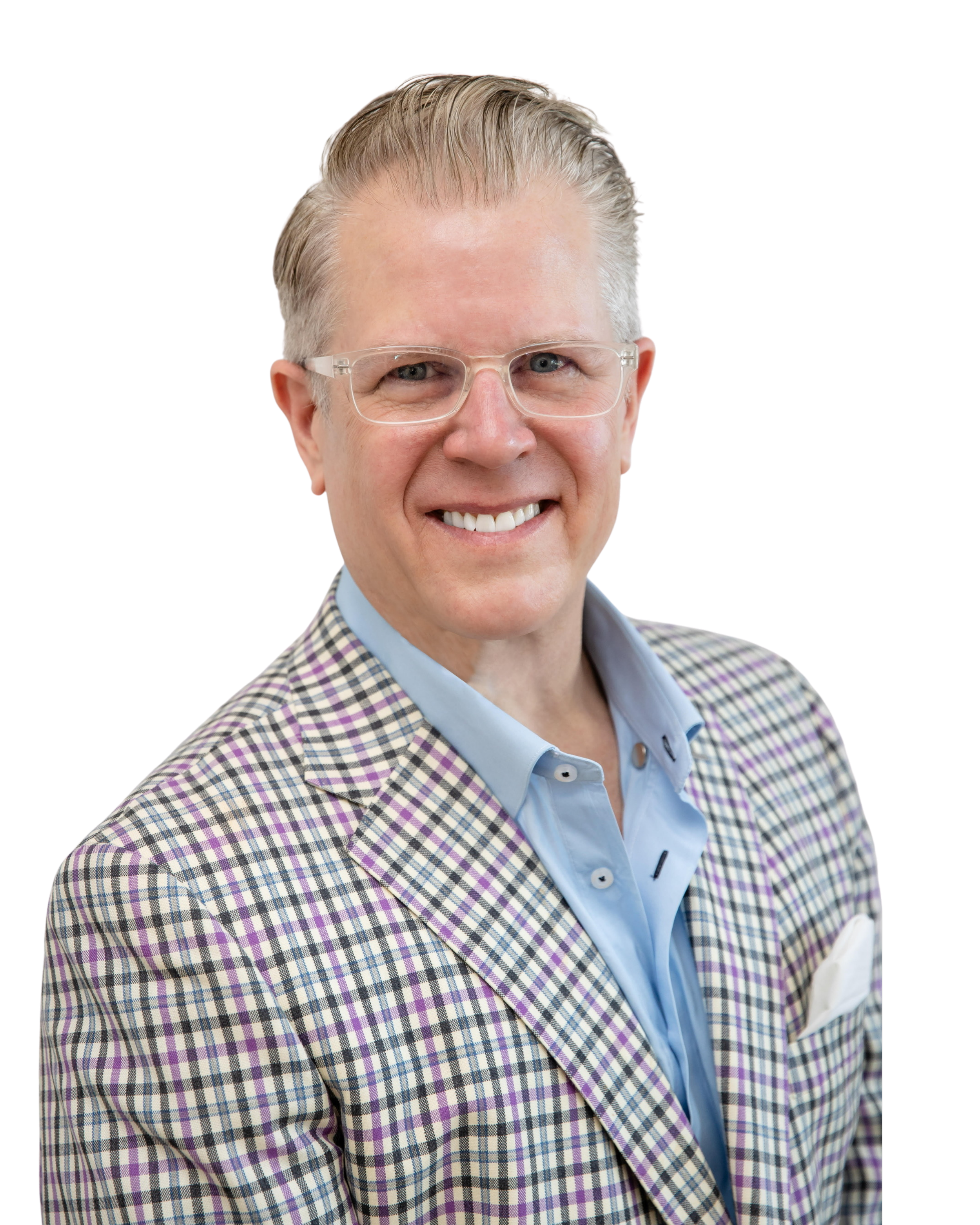 A smiling man with glasses, light gray hair, wearing a checkered blazer over a light blue shirt, holding a notebook and a pen.