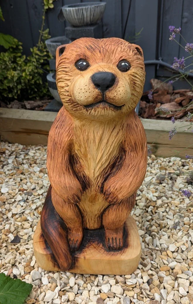 Handcrafted wooden otter chainsaw carving, individually carved from solid wood for the home or garden.