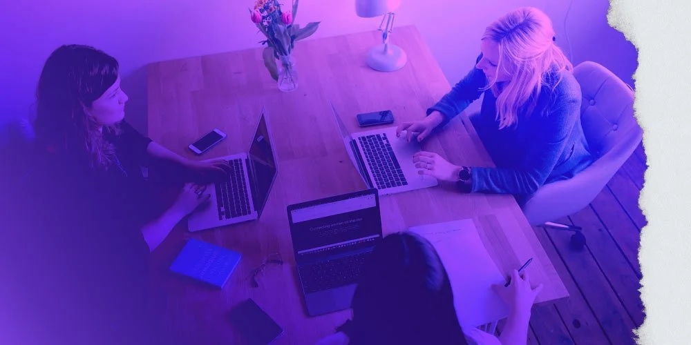 A group of 3 women collaborating around a table